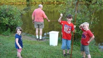 A group of people by a pond, one holding a fish.