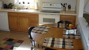 A kitchen with wooden cabinets, a microwave, a stove, and a dining table with placemats.