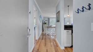 A hallway with wooden flooring, white walls, and a dining area with a table and chairs. - Award-Winning Resort Amenities | Lagoon Villa 21 (Isle of Palms)