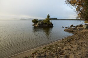 Un lago tranquilo con una pequeña isla que presenta un árbol y rocas.
