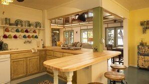 Una cocina con una isla de madera, taburetes de bar y un tapete colorido.