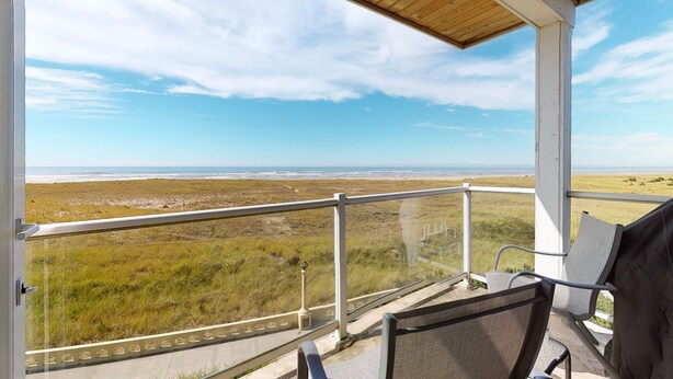 A balcony with a view of a beach and dunes. - OCEAN FRONT: SEAVIEW SERENITY: Seaside Vacation Homes, Inc Managed  (Seaside)