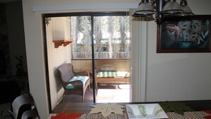 A dining area with a table set for two, a wicker chair, and a view through a glass door to an outdoor deck. - New furniture Beautiful Home! (Ruidoso)