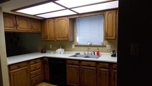 A kitchen with wooden cabinets, a dishwasher, a sink, and a window with blinds. - New furniture Beautiful Home! (Ruidoso)
