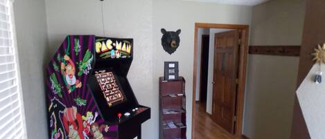 A room with a Pac-Man arcade machine, a bookshelf, and a bear head decoration.