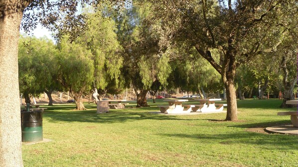 A park with picnic tables and benches, surrounded by trees.