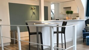 A modern kitchen with white cabinets, a central island, and a dining area with a white table and chairs.