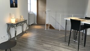 A modern kitchen with a dining area, featuring a white table, black chairs, and a decorative console table with a light.