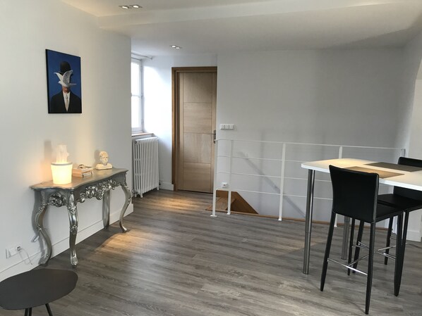 Une cuisine moderne avec un coin repas, comprenant une table blanche, des chaises noires et une console décorative agrémentée d’une lampe.