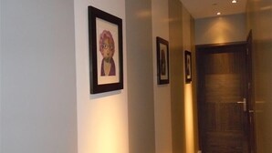 A hallway with framed artwork on the walls and a wooden door at the end.