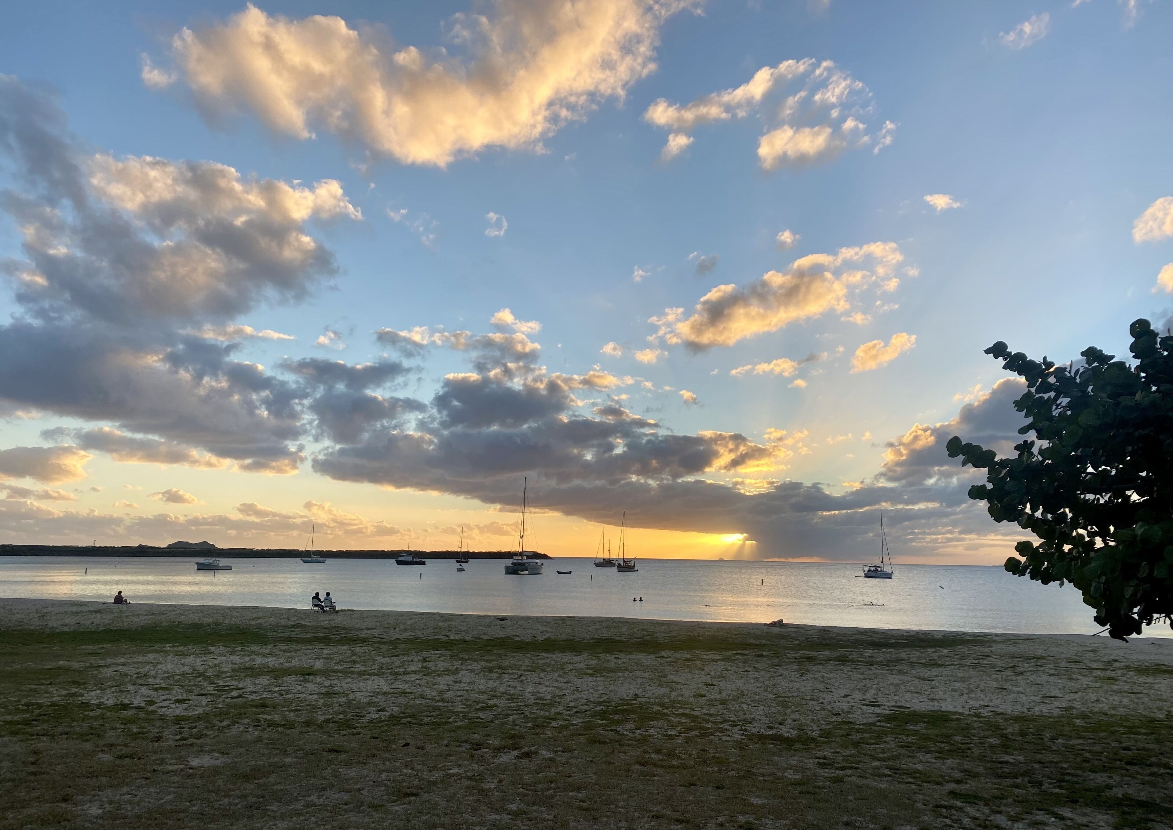 Una playa con barcos y un atardecer.