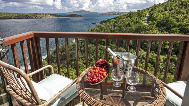 A balcony with wicker furniture, a basket of red grapes, a bottle of champagne, and two wine glasses. - Ocean-View 3BR Villa for Families and Groups (St Thomas)