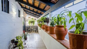 A covered outdoor area with potted plants, a bicycle, and a seating area with chairs.