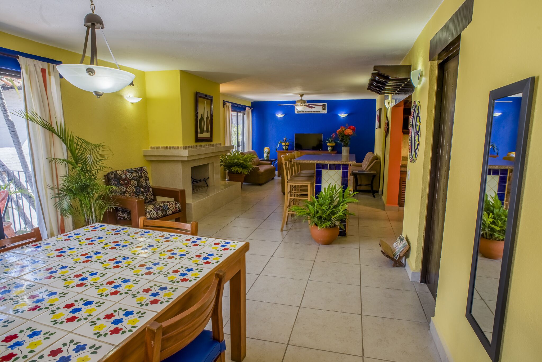 A dining area with a tiled table, chairs, and potted plants.