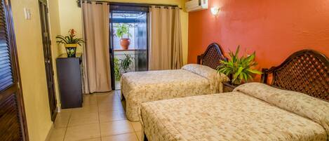 A hotel room with two beds, a ceiling fan, a potted plant, and a window with curtains.