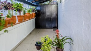 A covered outdoor area with a wooden ceiling, potted plants, and a bicycle.