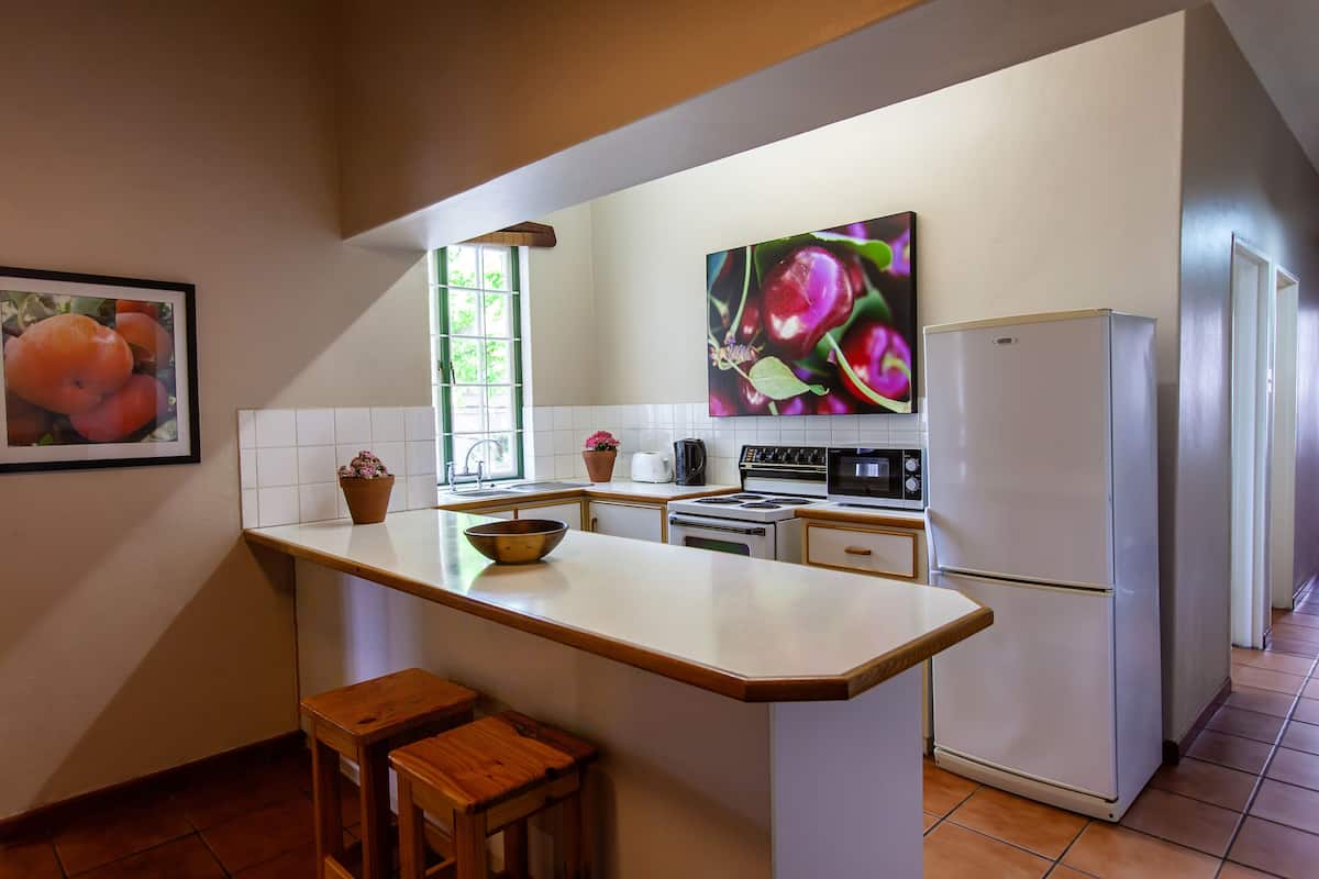 A kitchen with a central island, white appliances, and a window with a view.