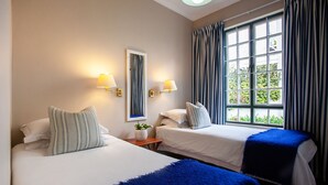 A hotel room with two beds, a large window with curtains, wall-mounted lamps, and a mirror. - The Habit Self Catering (Worcester)