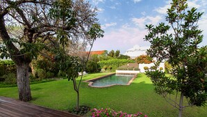 A well-maintained garden with a swimming pool, surrounded by trees and a wooden deck. - The Habit Self Catering (Worcester)
