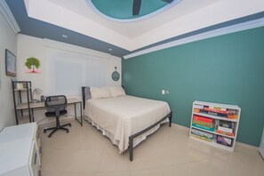Ein Schlafzimmer mit Bett, Schreibtisch, Stuhl und Bücherregal.