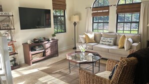 Una sala de estar con un sofá, una mesa de centro, un televisor y una estantería.