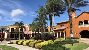 Hotel con patio que cuenta con palmeras, un toldo a rayas rojas y blancas y un letrero de 'No Estacionar'.