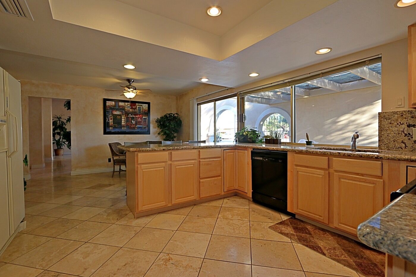 A spacious kitchen with a large island, built-in dishwasher, and ample natural light from large windows.
