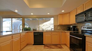 A modern kitchen with wooden cabinets, a dishwasher, a stove, and a microwave.