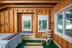 Relax in this serene room with a plush bed, a comfortable rocking chair, and a forest view.