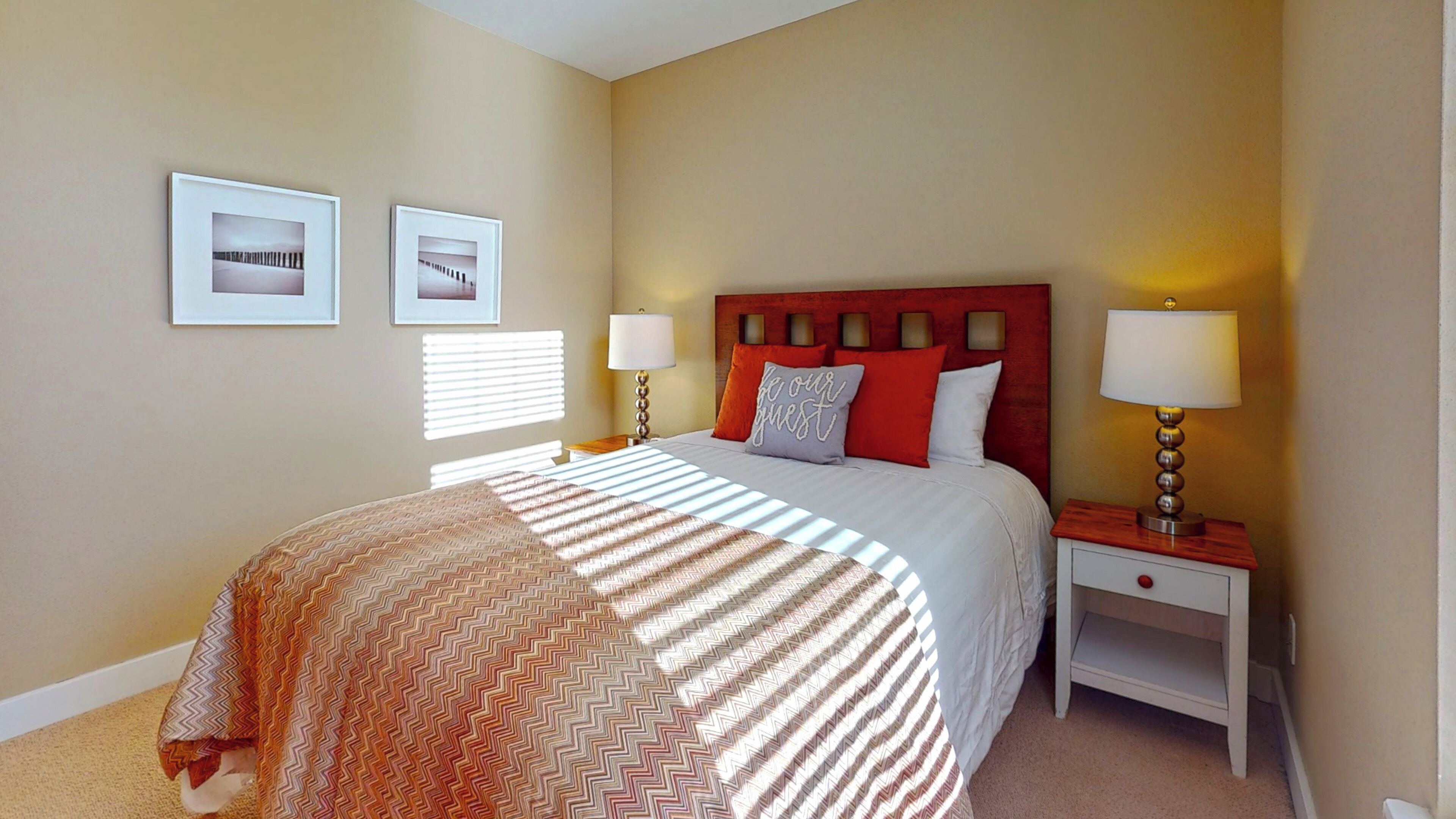 A neatly arranged hotel room with a large bed, two bedside tables, and a headboard with built-in lighting.