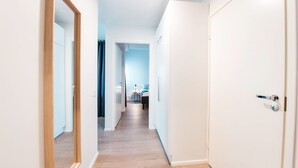 A narrow hallway with wooden flooring leading to a bedroom with a bed and a desk. - Forenom Serviced Apartments Helsinki Mansku (Helsinki)