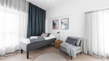 Un dormitorio moderno con una cama, un sofá, una mesita de noche y dos cuadros enmarcados en la pared.