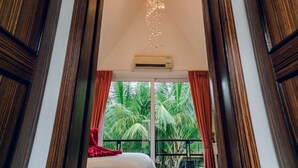 Habitación de hotel con balcón, cama y vista a palmeras.