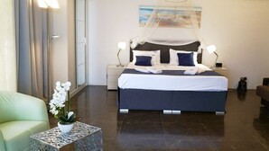 Una habitación de hotel moderna con una cama grande, lámparas de noche, una mesita de noche, un sofá y una planta ornamental de orquídea.