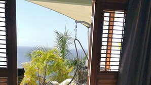Un dormitorio con cama, dos toallas, vistas a un jardín y una hamaca.