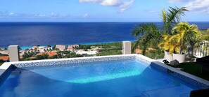A swimming pool with a view of the ocean and a coastal town. - Great View Villa Galant Curaçao (St. Willibrordus)