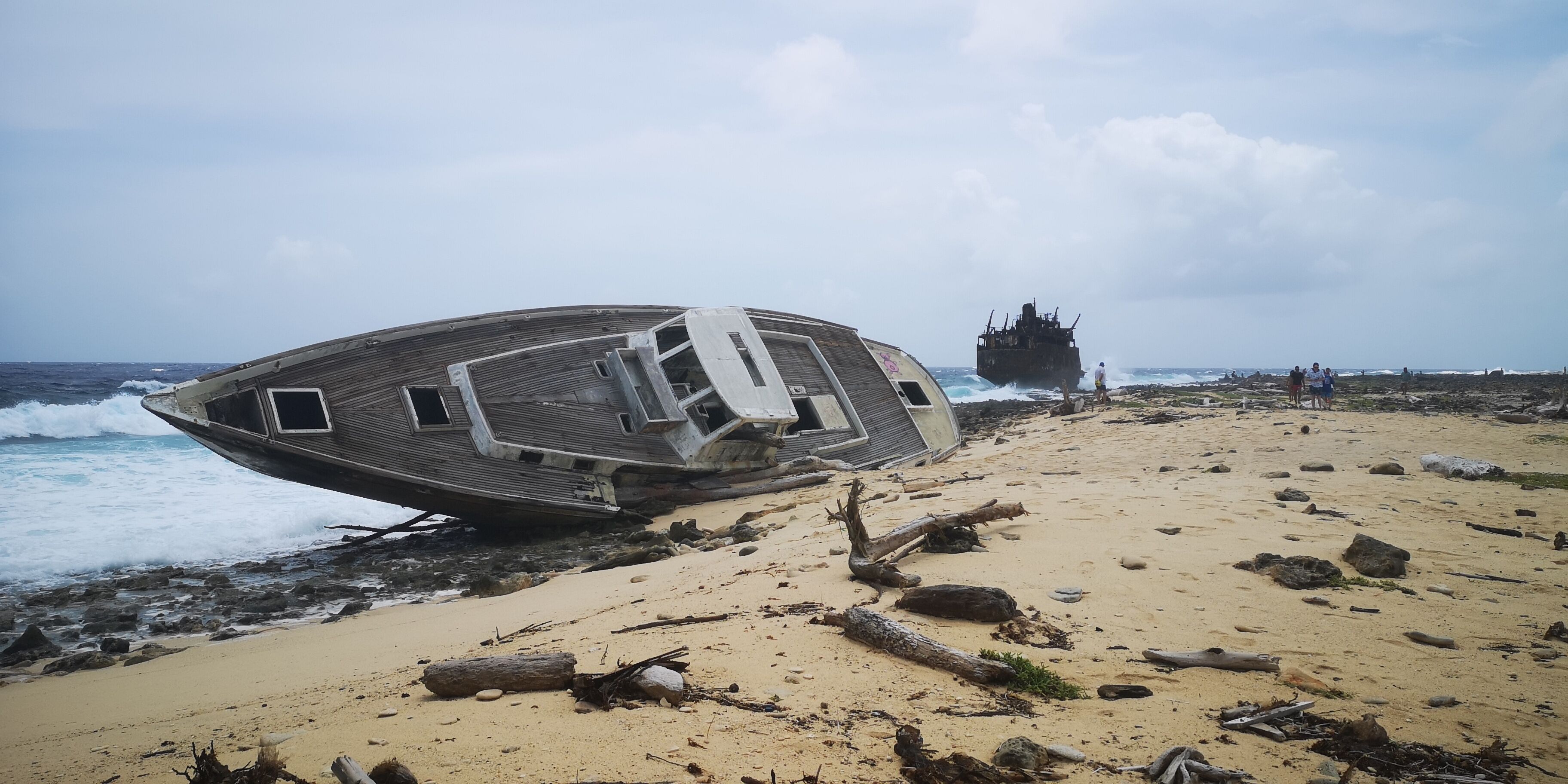 A shipwreck on a sandy beach with the ocean in the background.