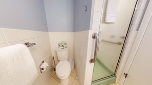 Une salle de bain équipée de toilettes, d’une barre d’appui et d’un porte-serviettes.