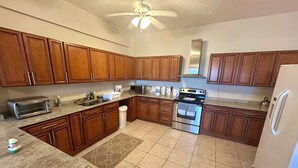 A kitchen with wooden cabinets, a stainless steel oven, a microwave, and a refrigerator. - Modern Oasis On Tropical (Vieques)