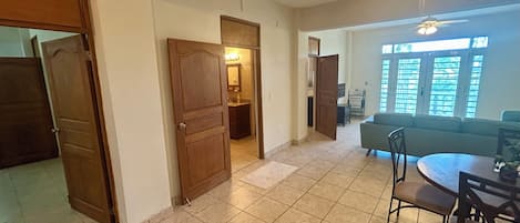 Uma sala de estar ampla com uma mesa de jantar, cadeiras, sofá e ventilador de teto.