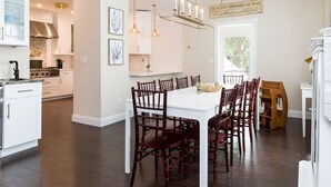 Una cocina moderna con armarios blancos, una isla grande y una zona de comedor con sillas de madera.