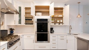 Una cocina moderna con armarios blancos, un horno doble, una estufa a gas y un lavavajillas integrado.