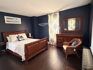 A bedroom with a wooden bed, a dresser, a chair, and a mirror. - Spacious Victorian Main House with Luxury Kitchen in Beautiful Historic District (Ocean City)