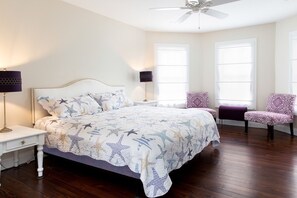 A bedroom with a bed, two nightstands, a ceiling fan, two windows, and two patterned chairs. - Spacious Victorian Main House with Luxury Kitchen in Beautiful Historic District (Ocean City)