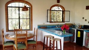A kitchen with a round dining table, chairs, a bar counter, and a tiled backsplash. - Casa Solana, Wonderful Large Outdoor Porch and many French Doors plus Pool (Sayulita)