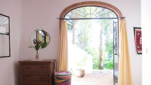 A room with a wooden dresser, a mirror, a colorful woven basket, and a view through an arched doorway to a garden. - Casa Solana, Wonderful Large Outdoor Porch and many French Doors plus Pool (Sayulita)