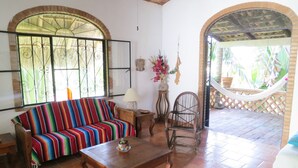 A living room with a colorful sofa, a wooden coffee table, and a hammock. - Casa Solana, Wonderful Large Outdoor Porch and many French Doors plus Pool (Sayulita)