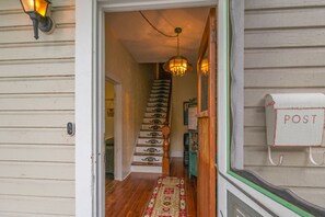 Staircase leads to a hallway with a patterned rug and a wall-mounted light fixture.