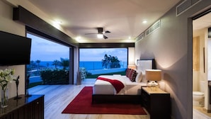 Een moderne slaapkamer met een groot bed, een televisie en uitzicht op de oceaan.
