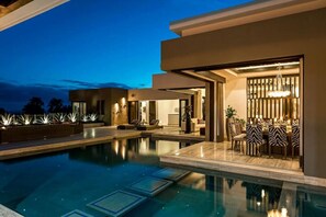 Et moderne poolområde med en klar pool, liggestole og et spiseområde med stole i zebramønster.